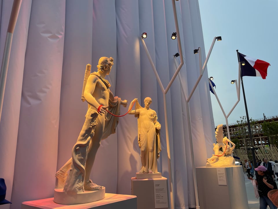 Statues of Apollo and Venus draped in a connecting red rope. In the background are Cupid and Psyche.