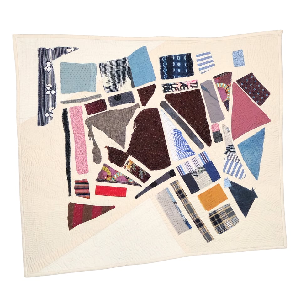 Photo of Meet Me at the Corner, a quilt made by Sarah Atlee. The quilt is approximately rectangular, with small scraps of fabric in many colors placed on an off-white background.