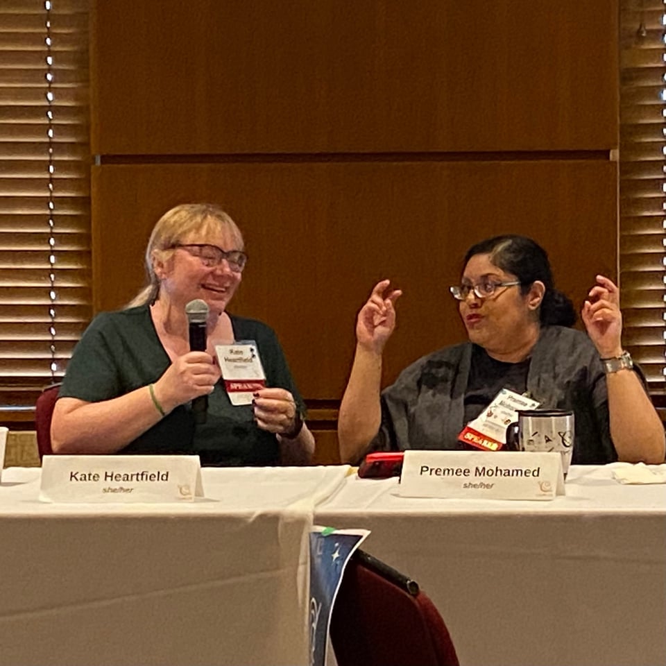 Two writers talking and smiling. I'm talking into a microphone and Premee is doing air quotes.