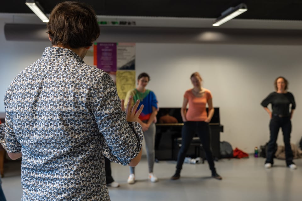 Gael teaching seen from the back with a few students in background