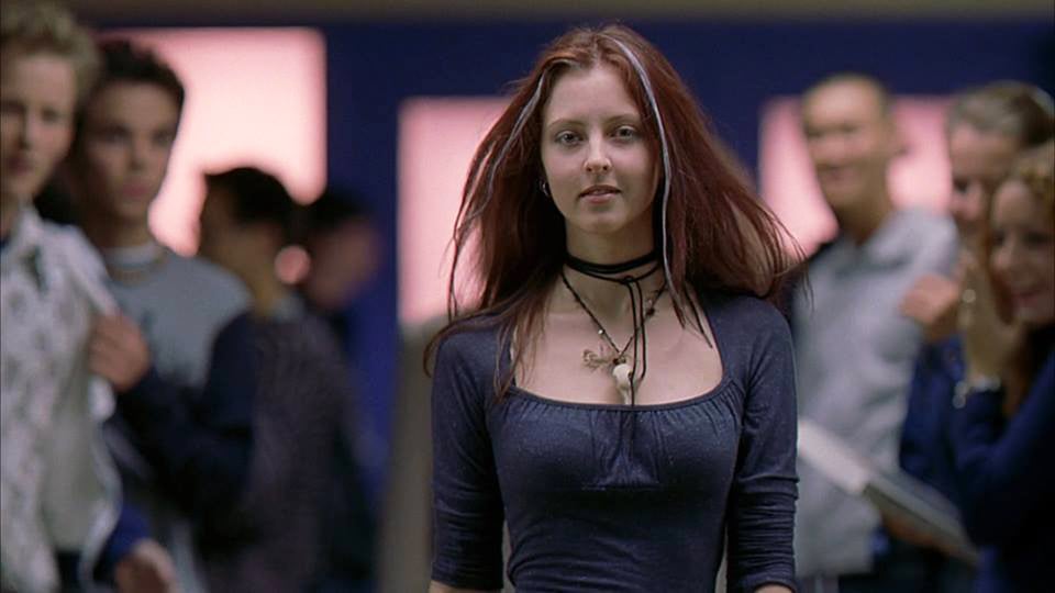 Ginger walks down the hall of her school with grey streaks in her red hair, a fetching goth outfit and a new attitude in Ginger Snaps