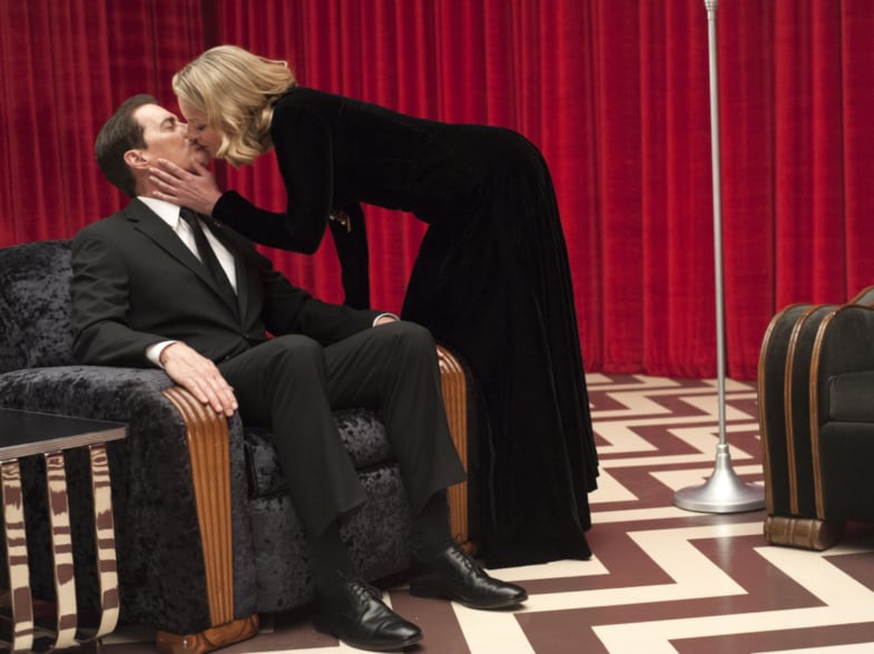 Kyle MacLachlan and Sheryl Lee in a shot from Twin Peaks: The Return. In the Red Room, Lee as Laura Palmer leans over and kisses MacLachlan as Agent Cooper while Cooper sits in a chair.