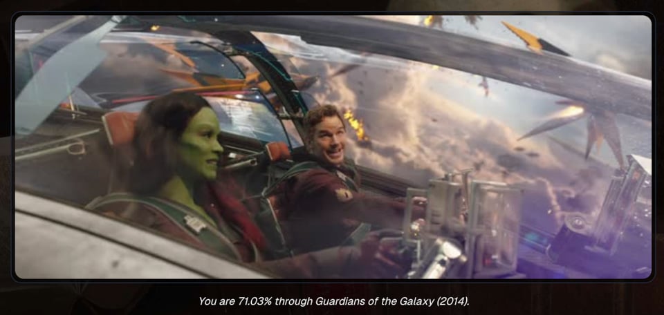 A screenshot of the movie, guardians of the Galaxy, showing a man and a green-skinned female alien inside the cockpit of a spacecraft, flying at great speed above the clouds of a planet, seemingly in battle with several alien craft flying in the distance. The sun is shining down on the clouds. Text at the bottom of the picture says "you are 71.03% through guardians of the galaxy (2014).”