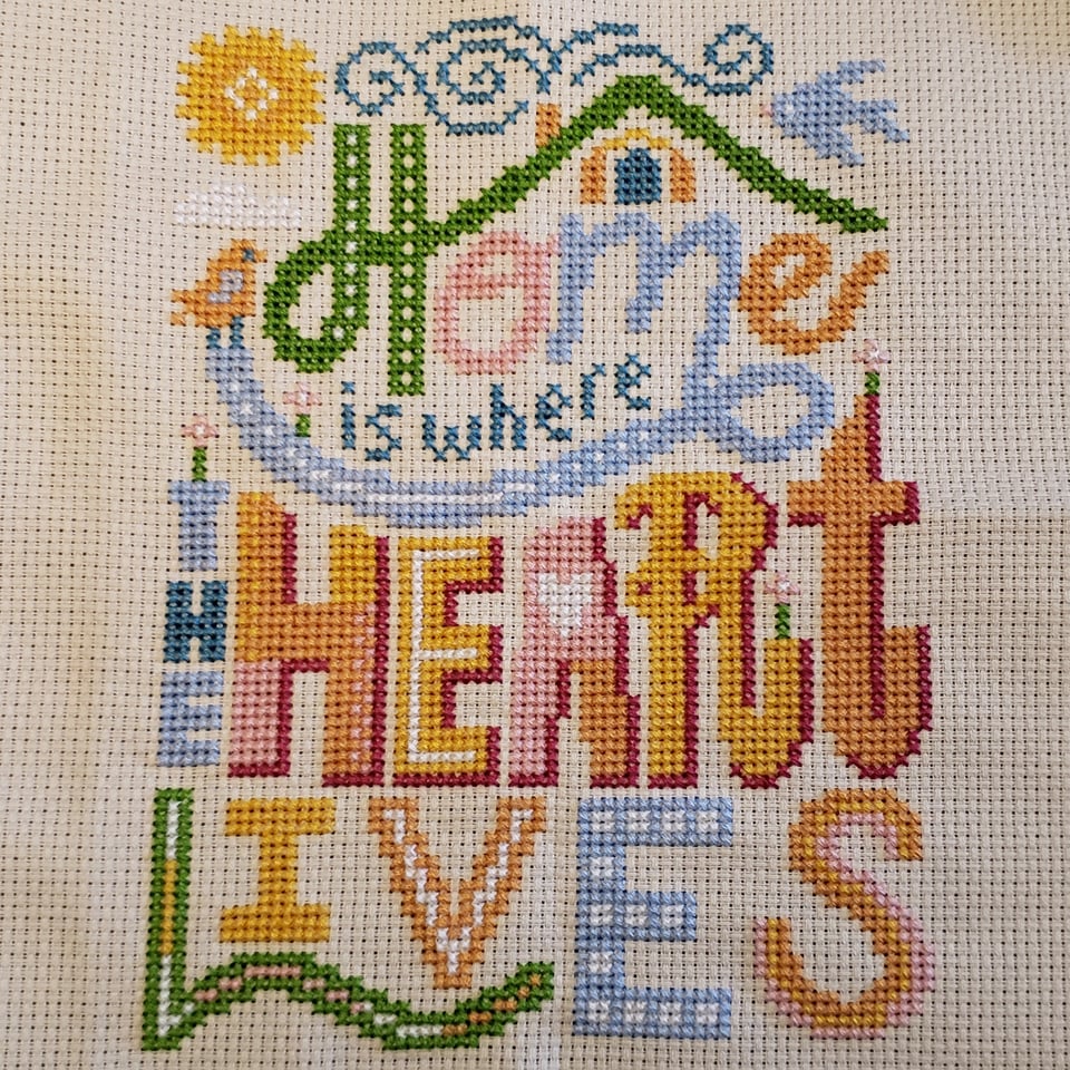 a cross stitch reading "home is where the heart lives"