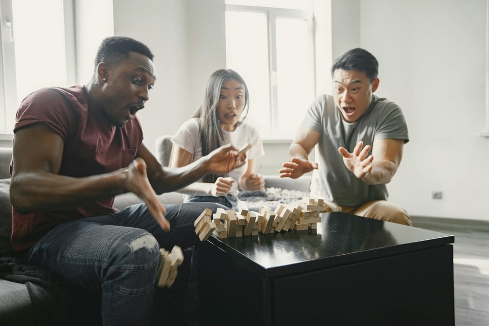 People playing Jenga as the tower falls down.