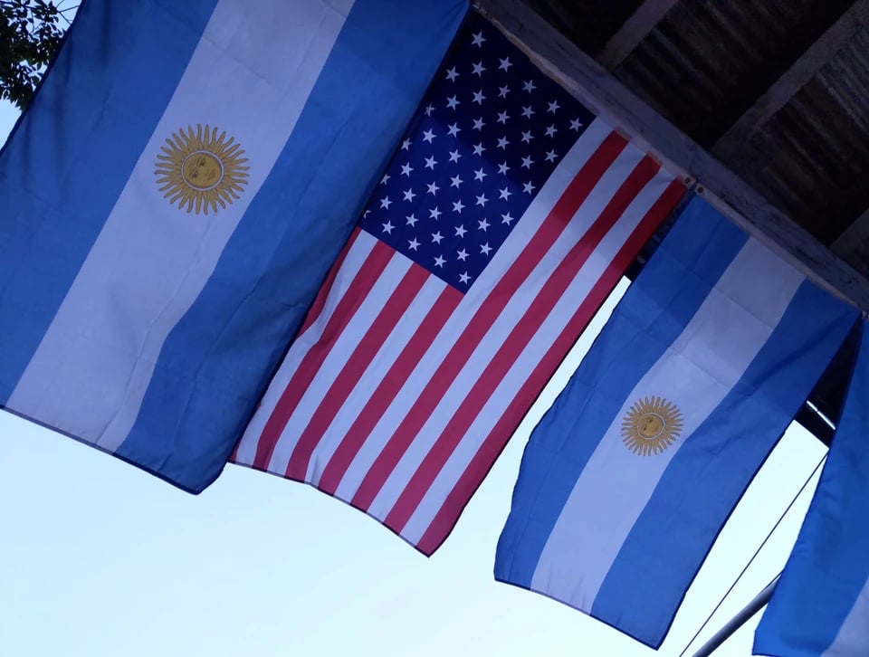 Three Argeintine flags and one American flag hanging from a construction shed.