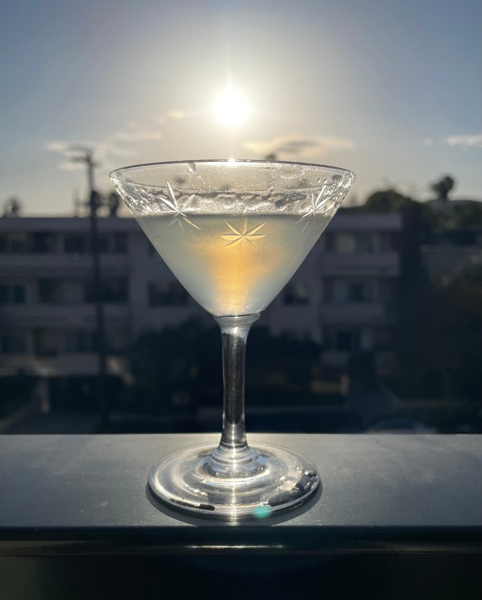 A small martini on a balcony with the sun just about to set above the glass