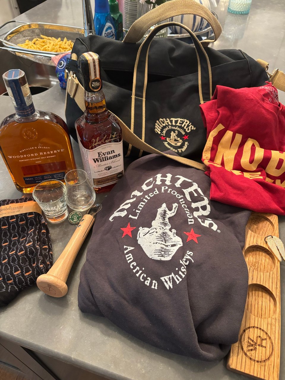 a bunch of bourbon bottles, shirts, gifts and stuff from neil's trip to louisville