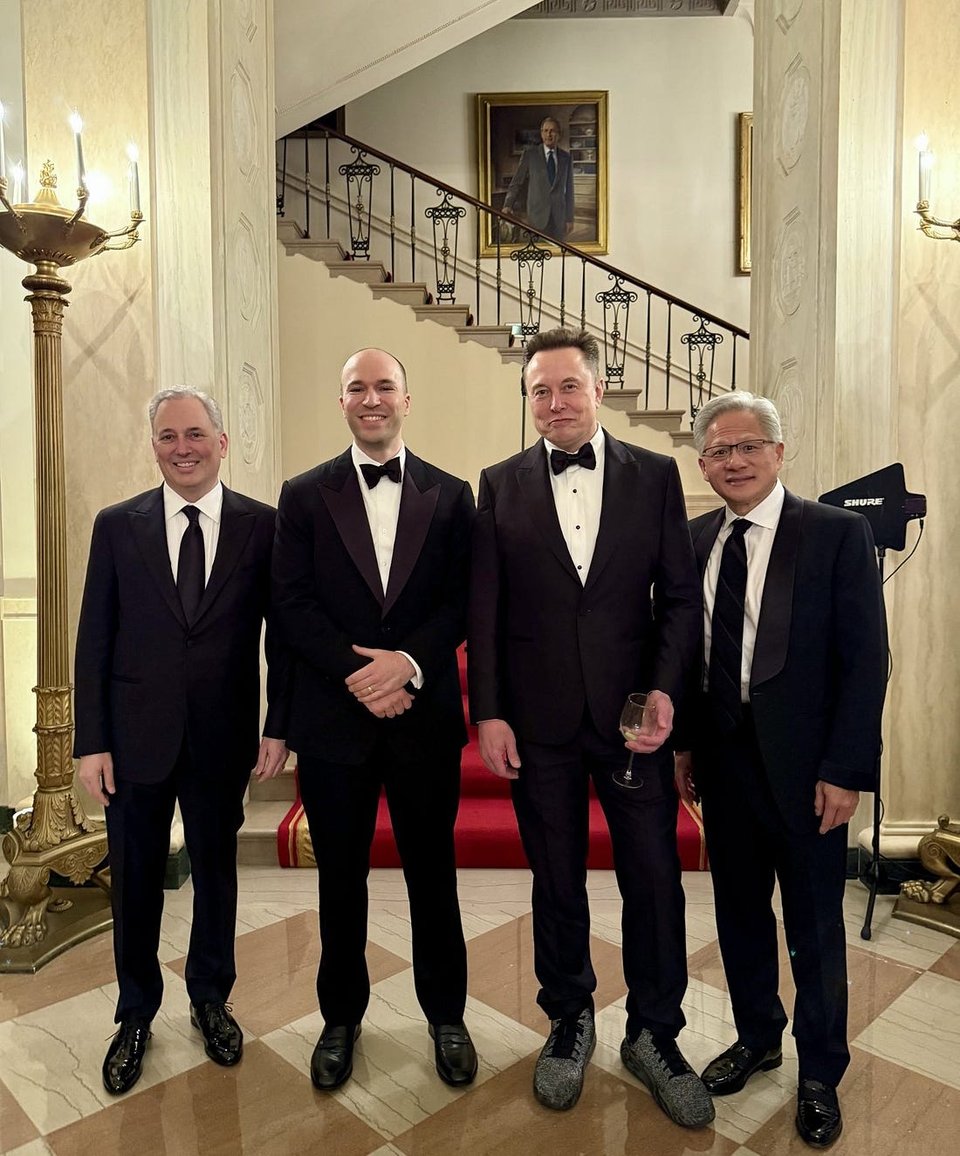 Left to right: David Sacks, Greg Brockman, Elon Musk, and Jensen Huang at the White House. Musk's comically large footwear resembles clown shoes.