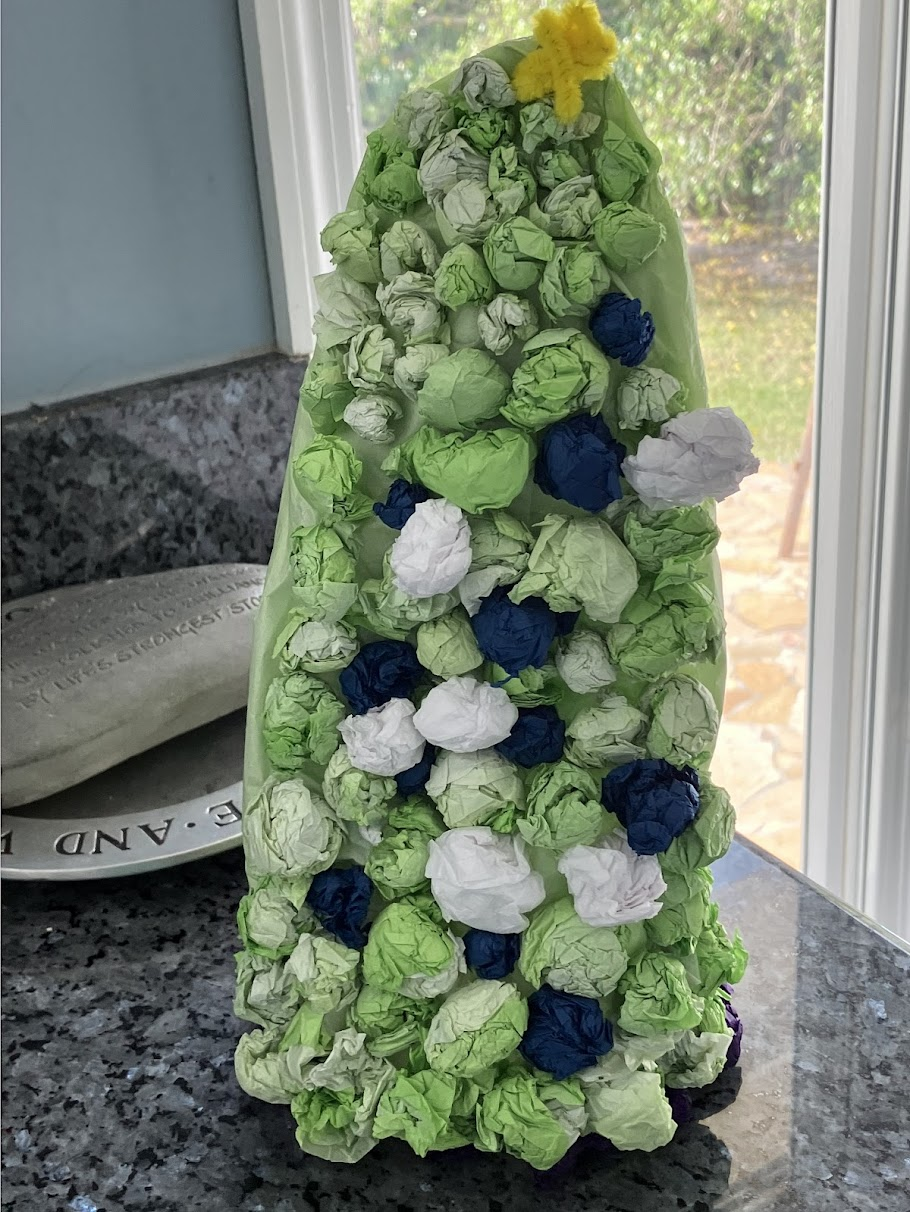 Handmade light green Christmas tree made out of tissue paper. There is also blue, white and purple tissue paper integrated into the whole.