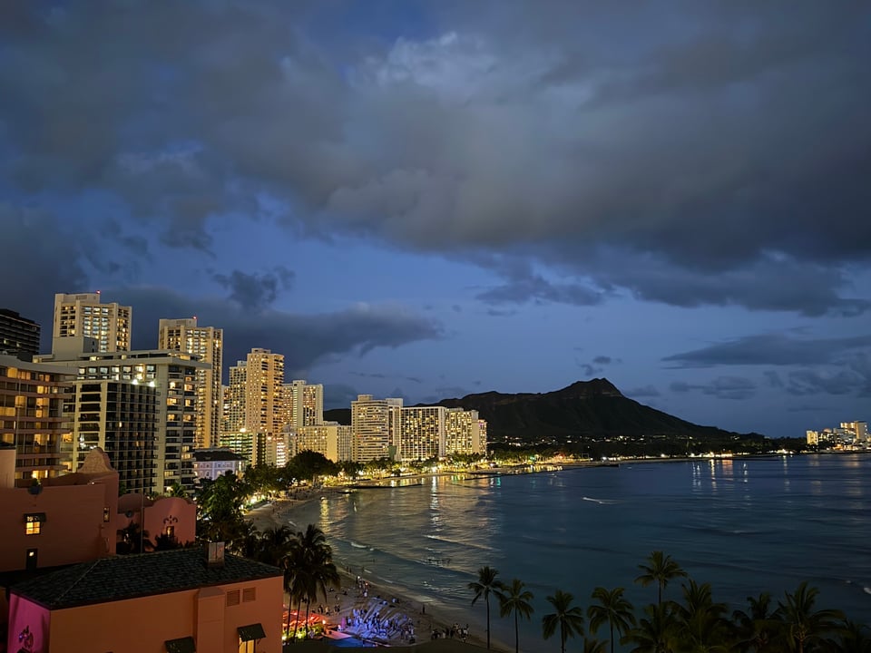 a view from the 10th floor of a hotel of Waikiki Beach and Diamond Head at night