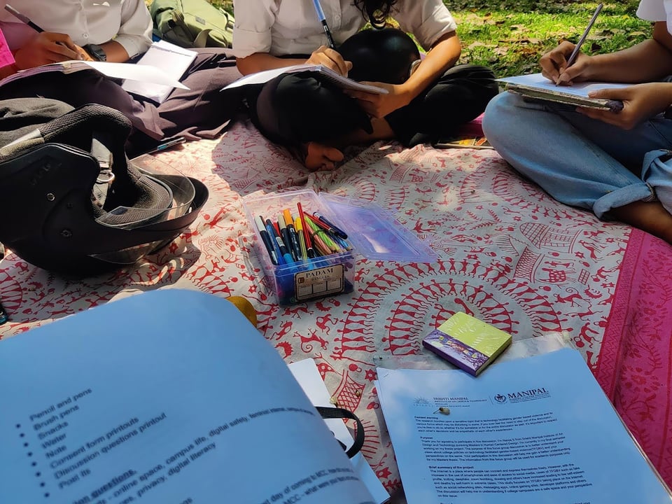 A group of people sitting on a blanket and engaging in a workshop activity.