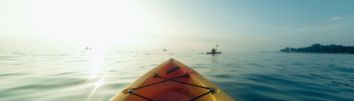 A kayak headed toward other kayakers in a sunny lake