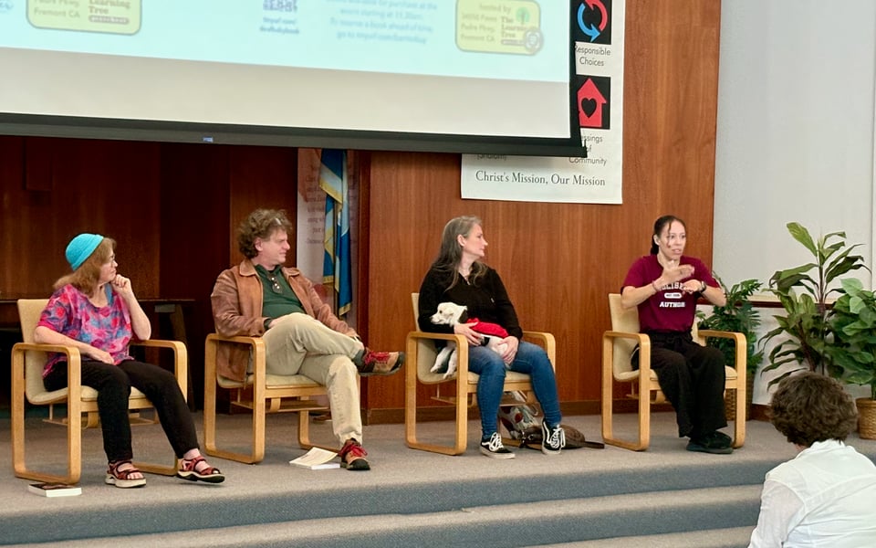 Photo of a panel discussion. Four people sit on chairs on a raised stage. An older white woman (Rachel Zemach), a middle-aged white man (Will Fertman), a middle-aged white woman (Mystery Guest X) and young Black woman (Noelle Wilder.)