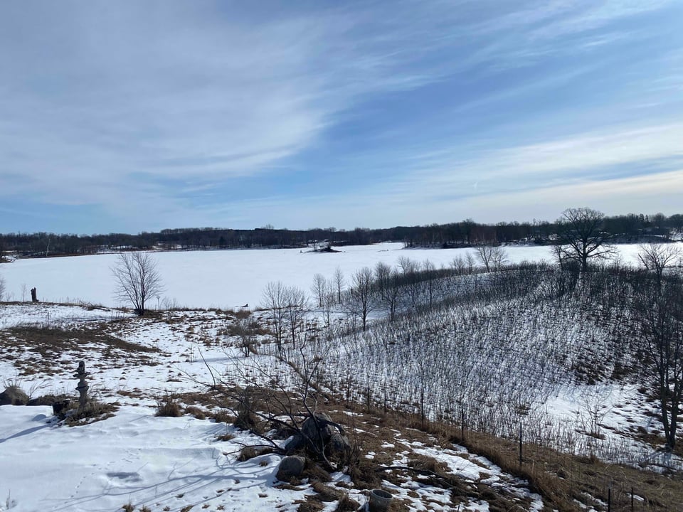 a landscape image of snow covered hills, lake and a blue sky