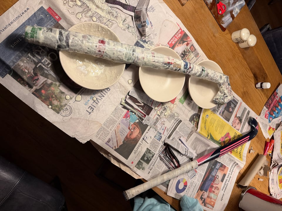 A Papier-mâché version of a hockey stick dries on three bowls.