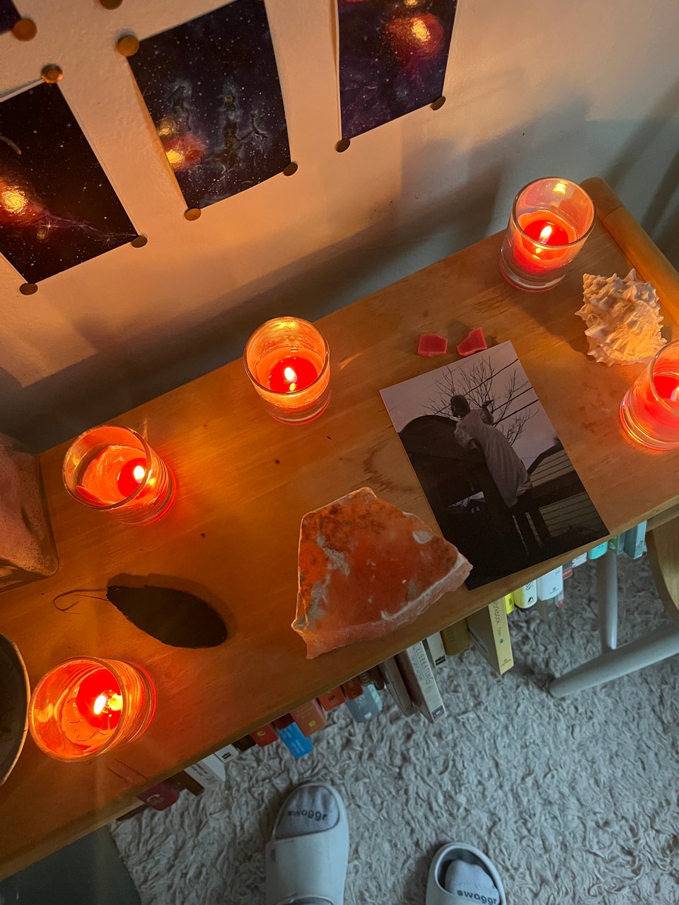 Beltane altar with burnt down, brightly lit pink-red candles, peach selenite, and a picture of Nola as a kid