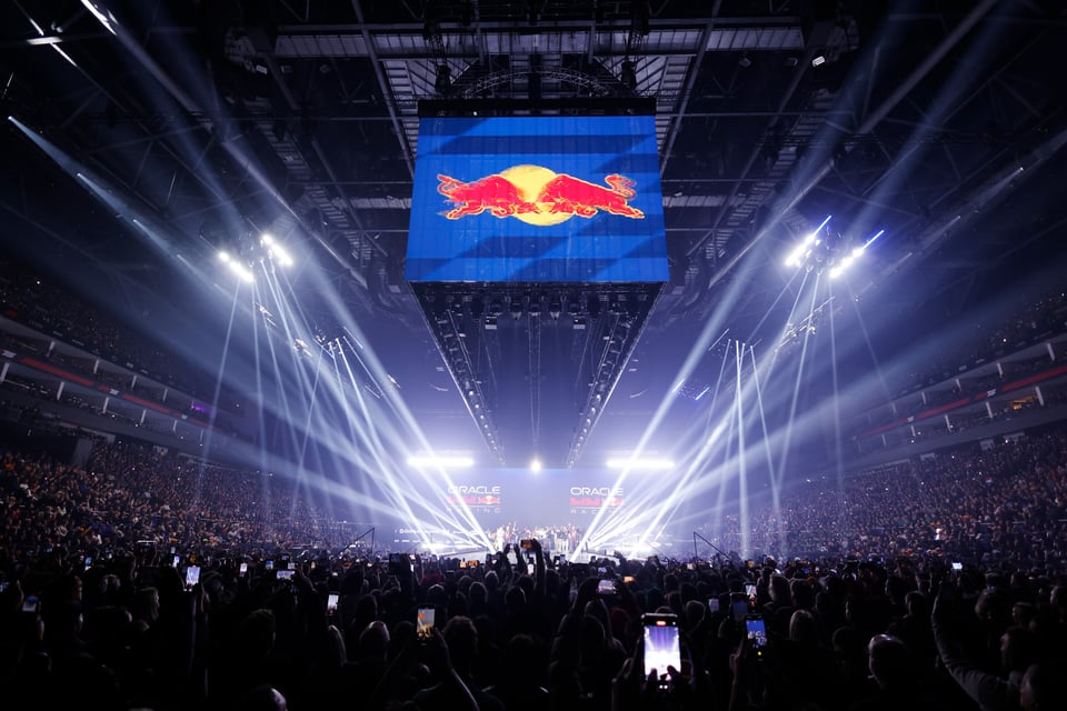 A photo of the Red Bull launch from the end of the stage through a crowd of fans who all have their phones out recording. It's all but impossible to see anything of the people or the car on stage.