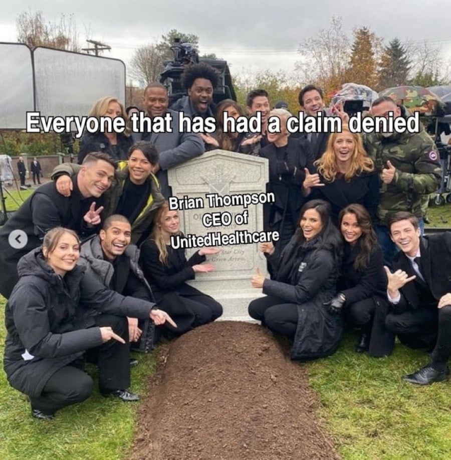 A large group of people posing around a cemetery headstone, pointing, giving thumbs ups and shakas, and grinning big. The crowd is tagged "Everyone that has had a claim denied" and the headstone is tagged "Brian Thompson CEO of UnitedHealthcare"