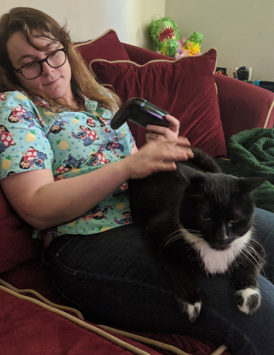Walter, a tuxedo cat, sitting on Von's lap while she has a Switch controller in hand.