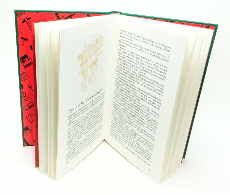 A spread from Six Centuries of Type & Printing: photo shows book standing, open to reveal the spread, with a glimpse at right of the black-on-red endpaper design