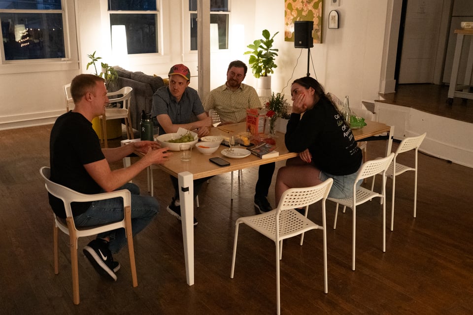 People discussing a book around a table.