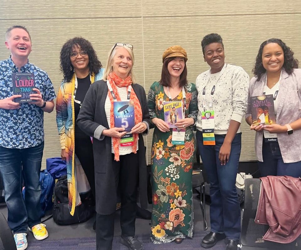 Five authors and one educator hold up books at teacher's conference