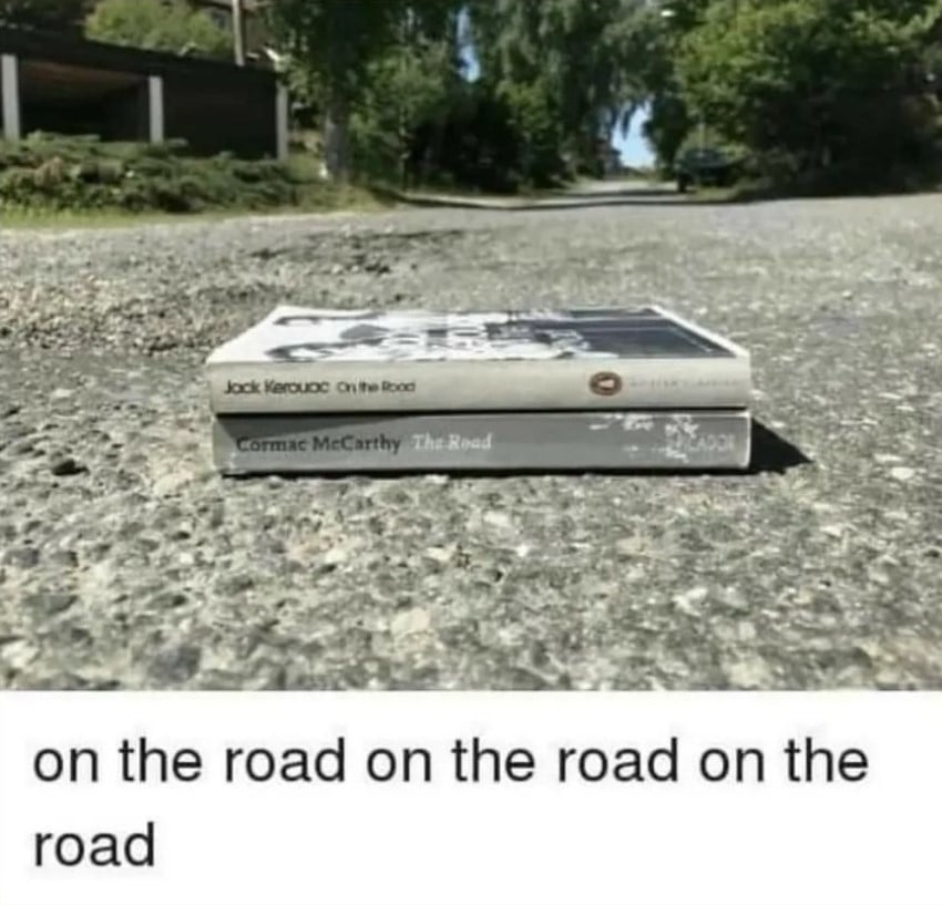 A photo of Jack Kerouac's On the Road stacked on top of Cormac McCarthy's The Road, both of which are sitting on the road. There are some trees in the background. The text beneath the photo reads: on the road on the road on the road.