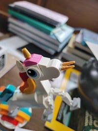 Lego unicorn with gold horns sticking straight out of its nostrils.