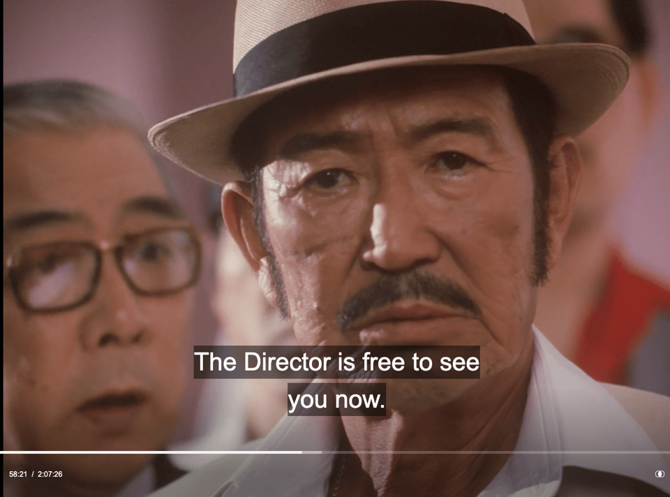 screen shot of angry yakuza with english caption of different bureaucrat saying "Thedirector is free to see you now"