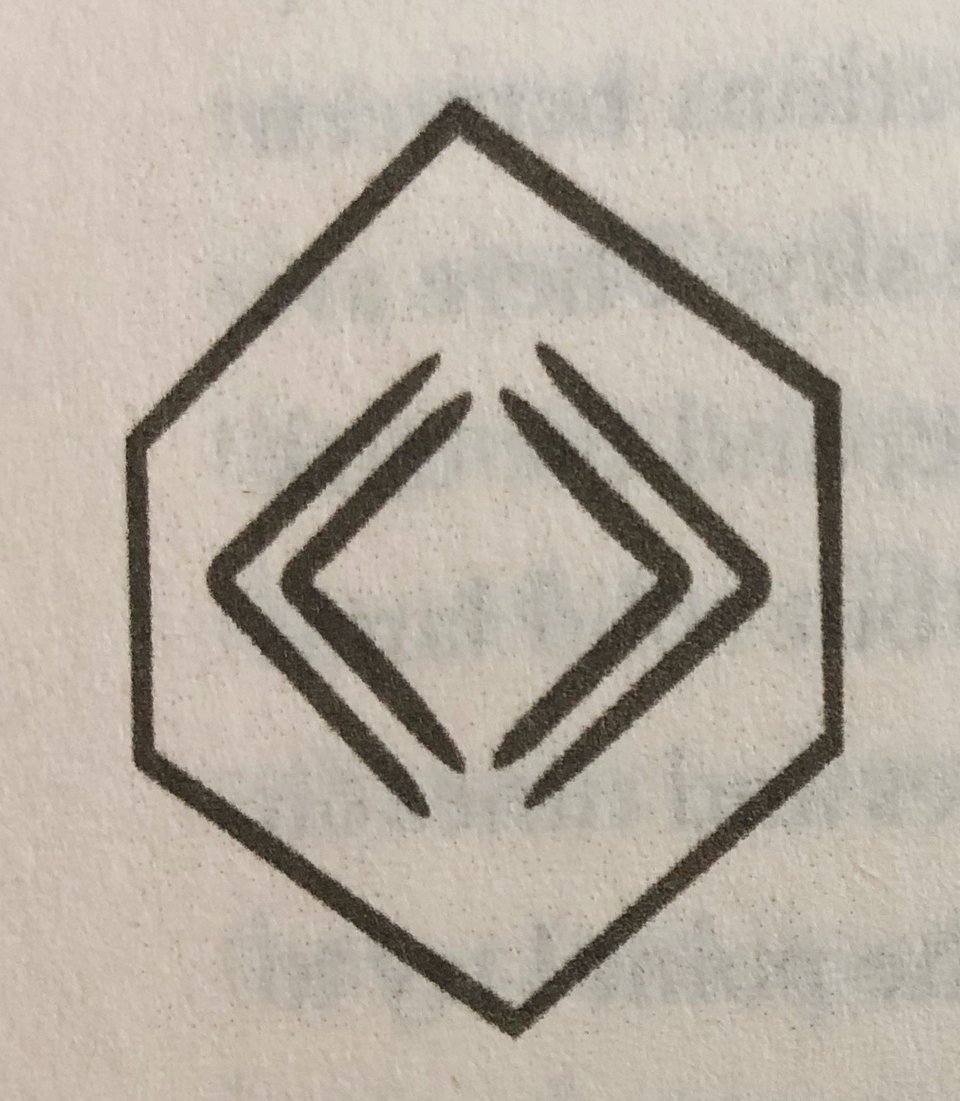 A hexagon. Inside the hexagon two chevron shapes point to the left, and two chevron shapes point to the right.