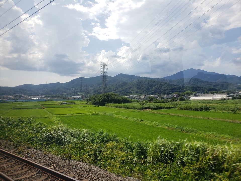 A view out the shinkansen window at the green countryside.