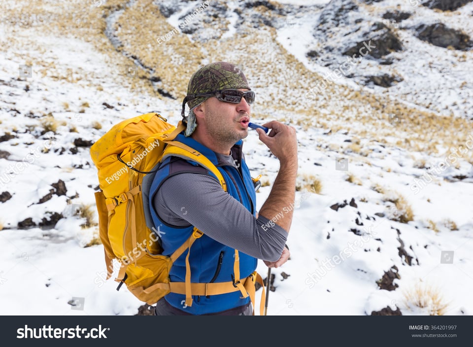 A stock photo (with watermark) of a backpacker in the snow applying lip balm in a kind of cunty manner