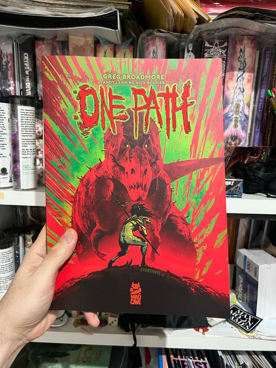 Cover of a graphic novel depicting a lone warrior woman with a spear facing a tyrannosaurus rex