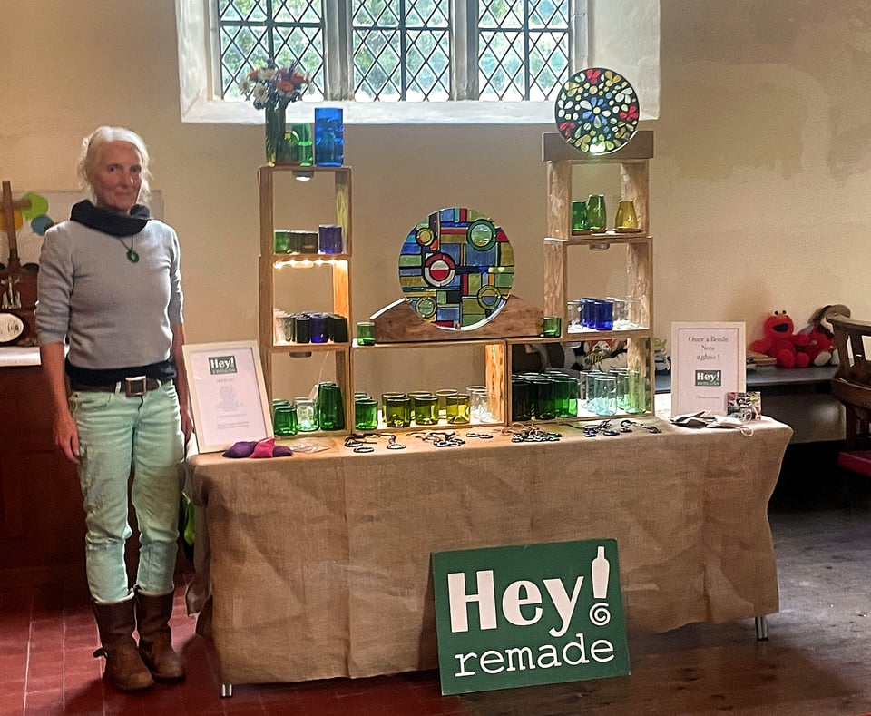 An artist beside a display of glass artwork.