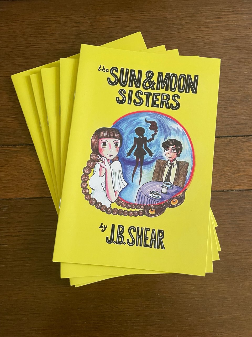 a stack of physical copies of The Sun & Moon Sisters