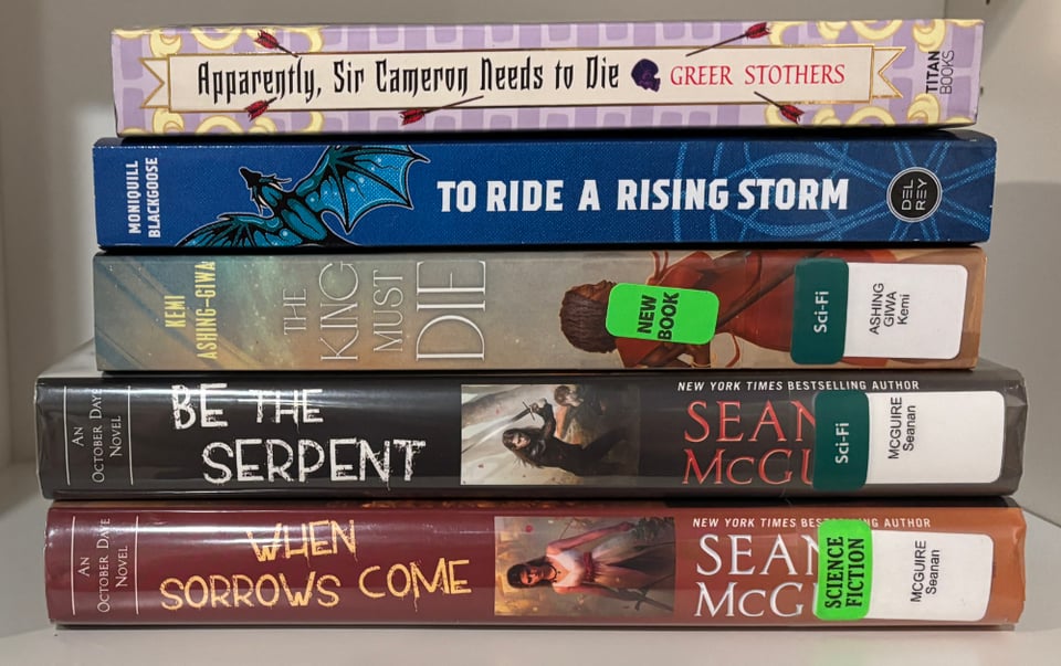 Stack of books, spines out: Apparently Sir Cameron Needs to Die, To Ride a Rising Storm, The King Must Die, Be the Serpent, and When Sorrows Come