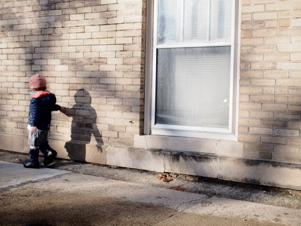 Sona touching her shadow on the brick wall