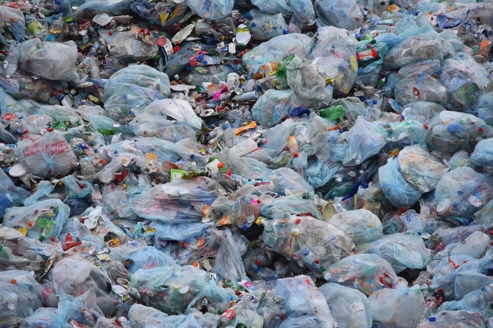 Image of plastic bags filled with plastic trash interspersed with unbagged plastic trash