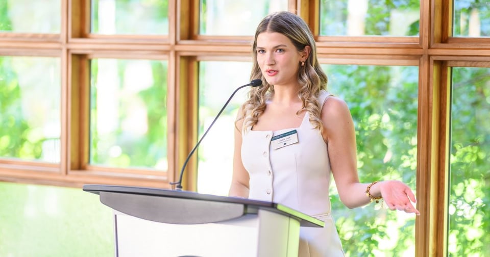Taylor Toth speaking at lectern inside of Cowles House