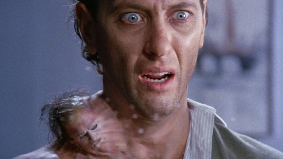 Richard E. Grant in How To get Ahead in Advertising, looking horrified at the giant boil on his neck. The boil has a face, hair and a mustache.