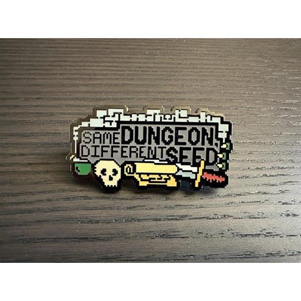 An enamel pin: "Same dungeon, different seed", with a dungeon map on top and a variety of adventuring items below it