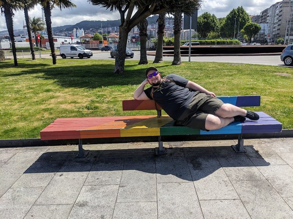 Grayson laying down on a rainbow-colored bench in Vigo, Spain