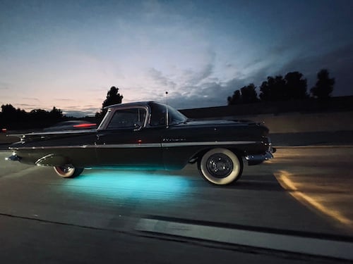a vintage black El Camino driving on the freeway