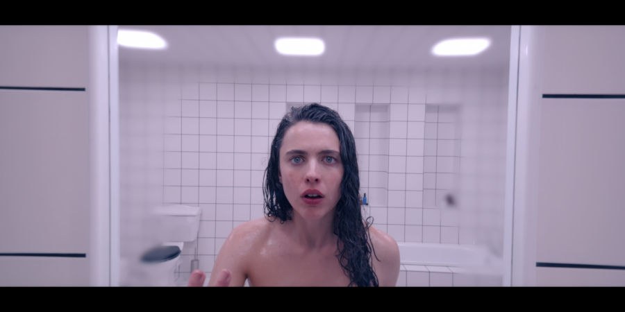 Margaret Qualley as Sue looks into a mirror with a deeply confused look on her face - unable to believe she's been born, or born so beautiful?