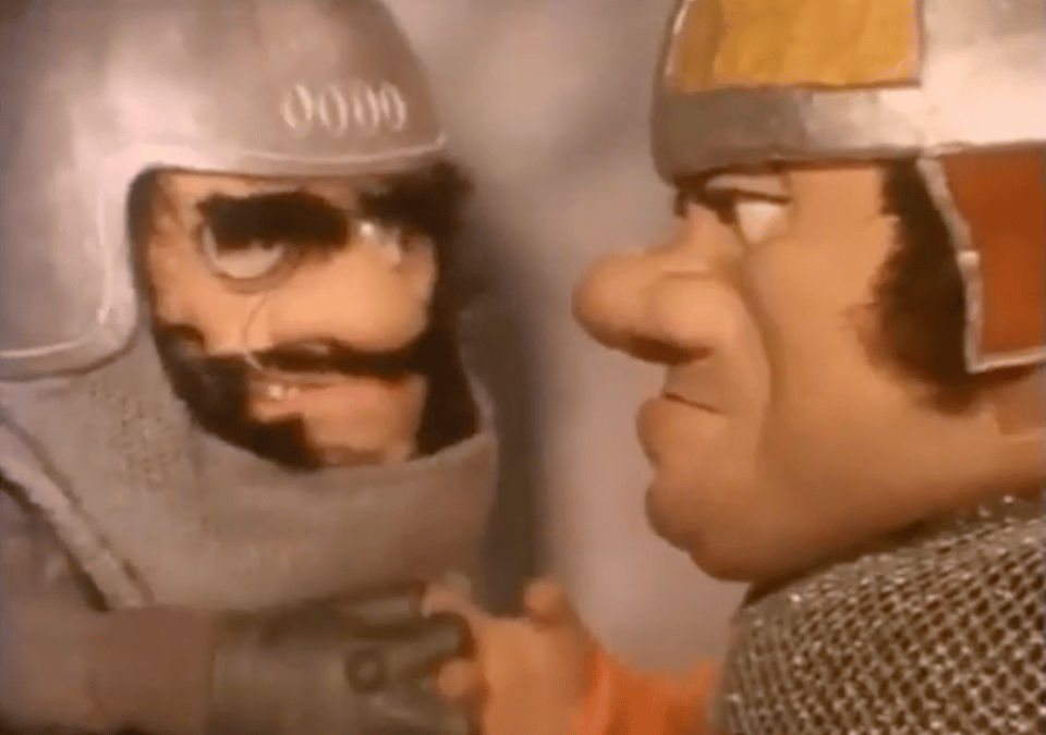 Screenshot of a children's TV show. Two puppet characters in suits of armour shake hands while giving each other very mean looks.