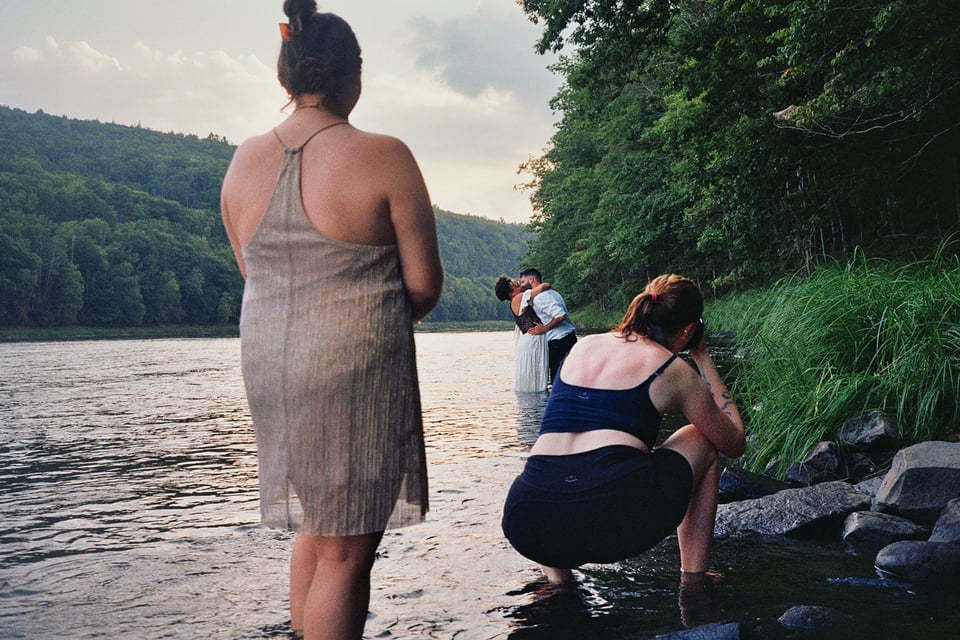 beth taking a pic of al and bel, all of them in the lake. sarah stands next to beth ready to help her up.