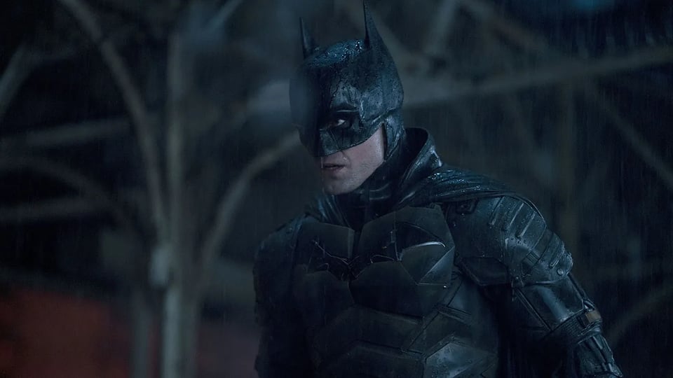 Robert Pattinson as Batman: wearing a dark costume against a dark background in low lighting
