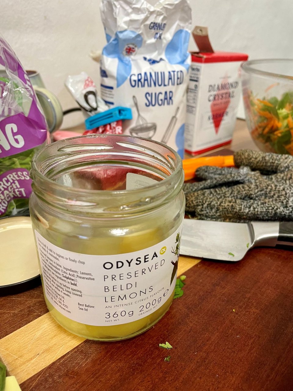 Ingredients with a jar of preserved lemons in the foreground