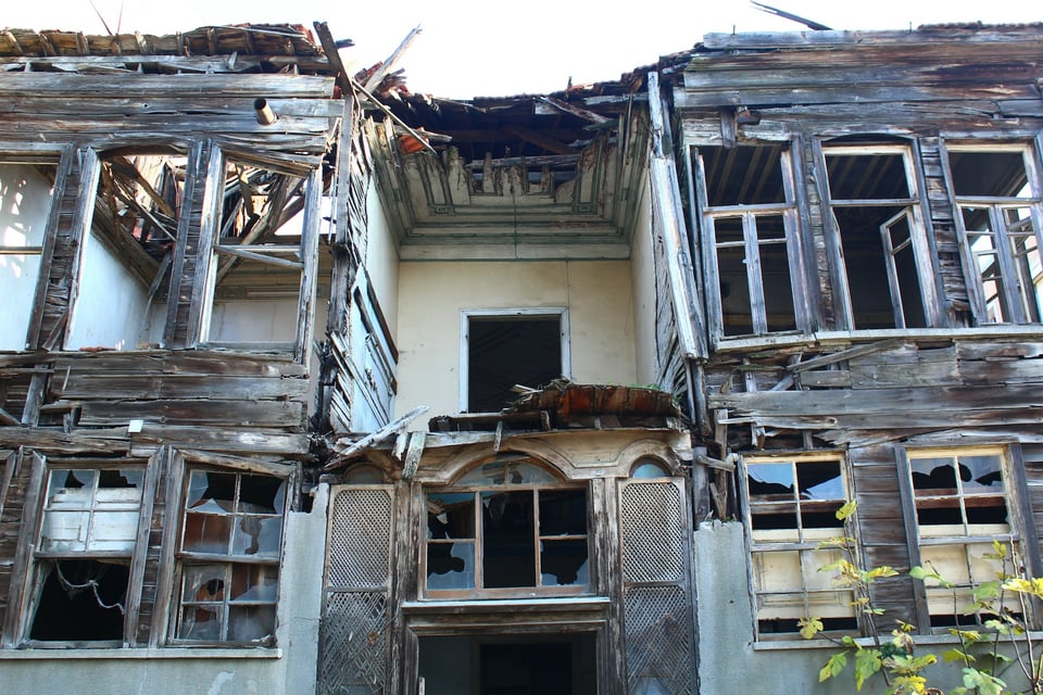 A run-down, abandoned house with broken windows. Photo by Seval Torun on Unsplash.